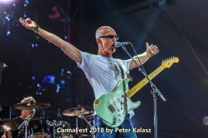 Kim Mitchell singing with arms wide apart, engaging the crowd during a live performance.