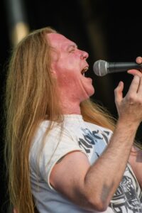 Daniel Nargang of Kick Axe singing with his head back during a live performance.